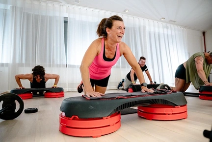 Vrouwen en mannen maken plezier tijdens een HIIT interval- en cardiotraining in de fitnesszaal van LAGO CLUB Grimbergen. 