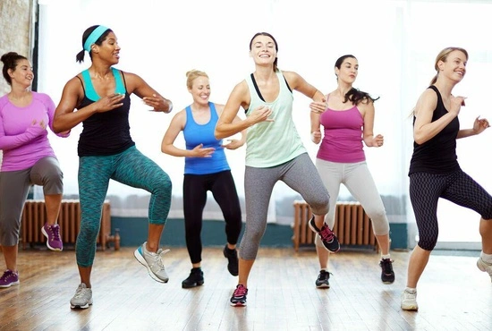 Vrouwen dansen en maken plezier tijdens een groeples Zumba fitness in de fitnesszaal van LAGO CLUB Grimbergen.