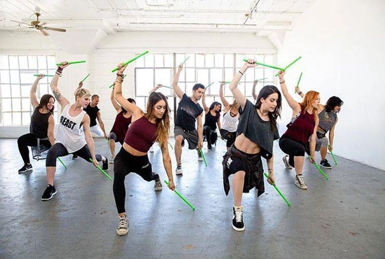 Vrouwen maken plezier tijdens een groepsles gebaseerd op dans, yoga en pilates in de fitnesszaal van LAGO CLUB Grimbergen.
