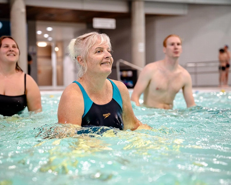 Vrouwen en mannen volgen een aquagymles in groep in het zwembad van LAGO CLUB fitness Grimbergen. 